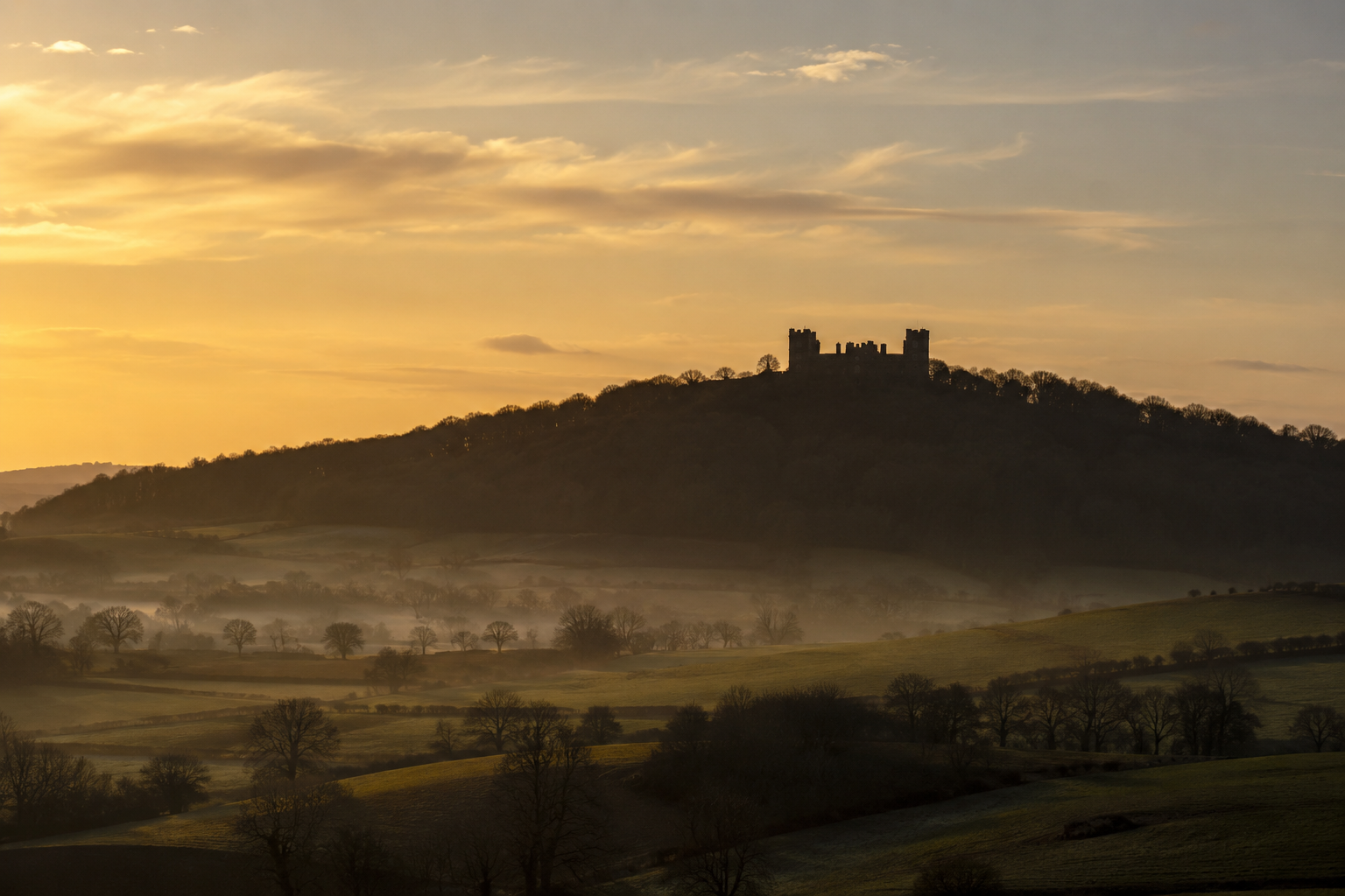 Riber Castle silhouetted on Riber Hill above the Derbyshire landscape at golden hour