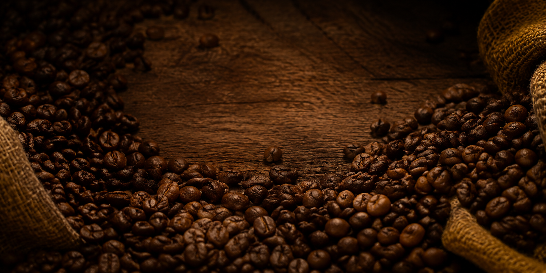 Roasted coffee beans on warm timber with unbranded burlap texture