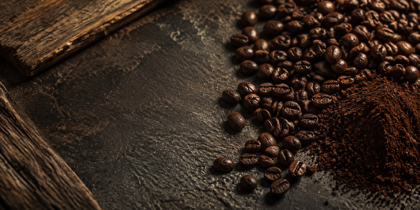 Roasted whole coffee beans and freshly ground coffee on dark stone